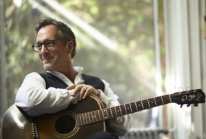 Richard Shindell with guitar in front of window